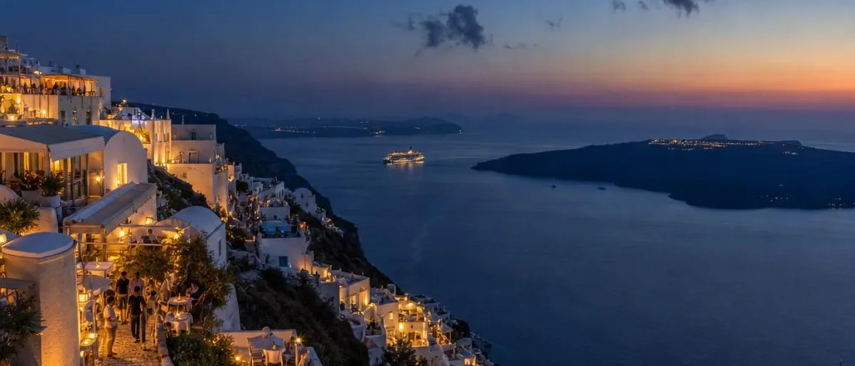Santorini nightlife in Fira with illuminated white caldera buildings above the Aegean Sea after sunset