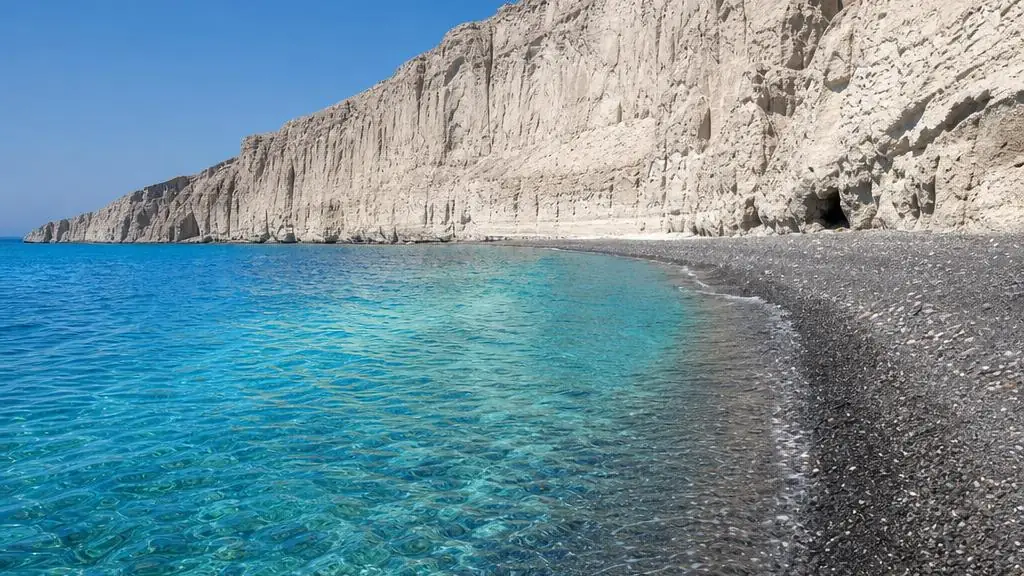 White Beach in Akrotiri, Santorini, with pale volcanic cliffs, a dark pebble shore and turquoise Aegean water
