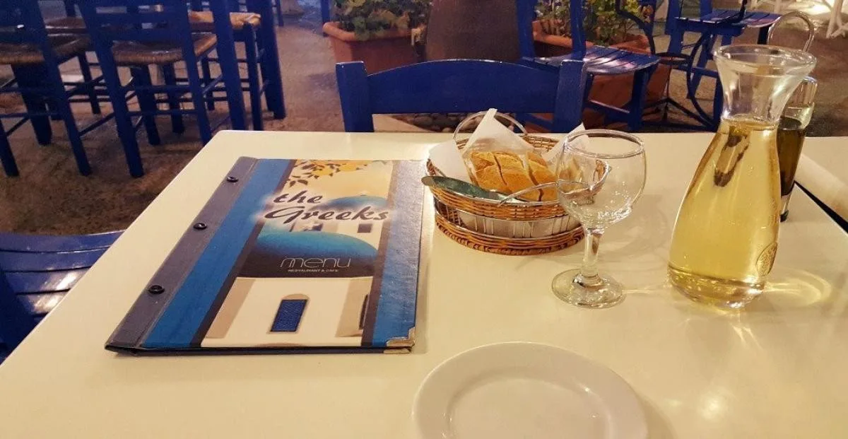 Table set with The Greeks menu inside the blue and white restaurant